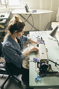 在时装工作室使用缝纫机的女裁缝图片