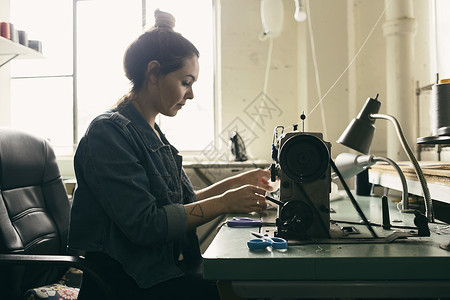 服装工作室使用缝纫机的年轻女裁缝创造力高清图片素材