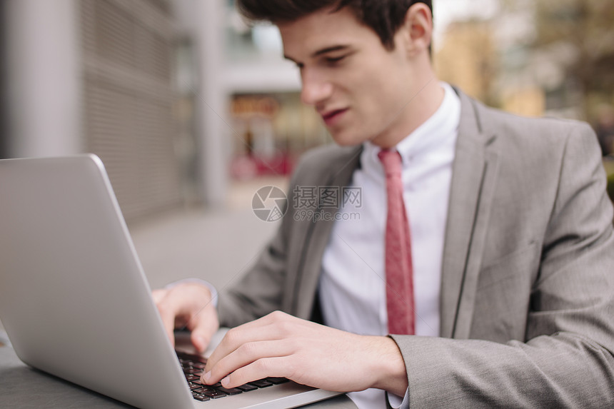青年城市商人在行咖啡厅用笔记本电脑打字图片