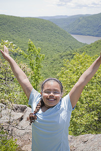 女孩在山顶举起手微笑图片