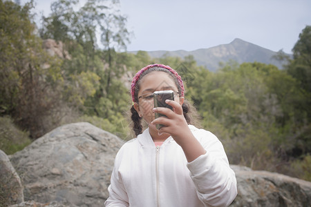在山顶玩手机的年轻女孩图片