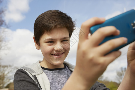 使用智能手机自拍的微笑少年男孩图片