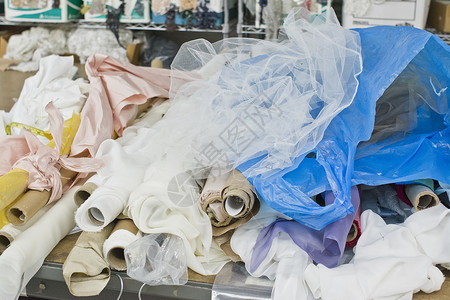 时装设计桌上堆放的滚纺织品图片