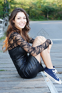 一位年轻女坐在镜头下微笑的膝跪肖像图片