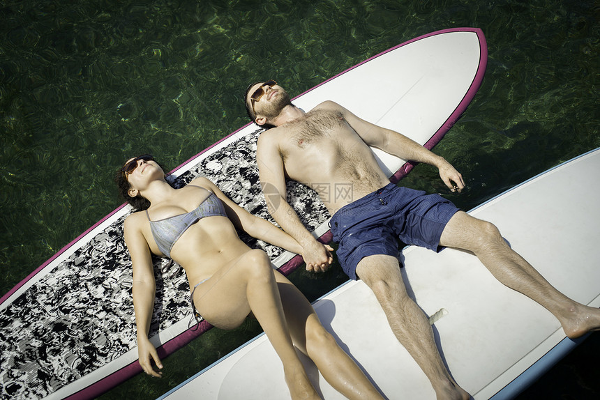 在桨板上做日光浴的年轻夫妇图片