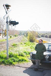 铁路旁靠着车前的成年男子图片