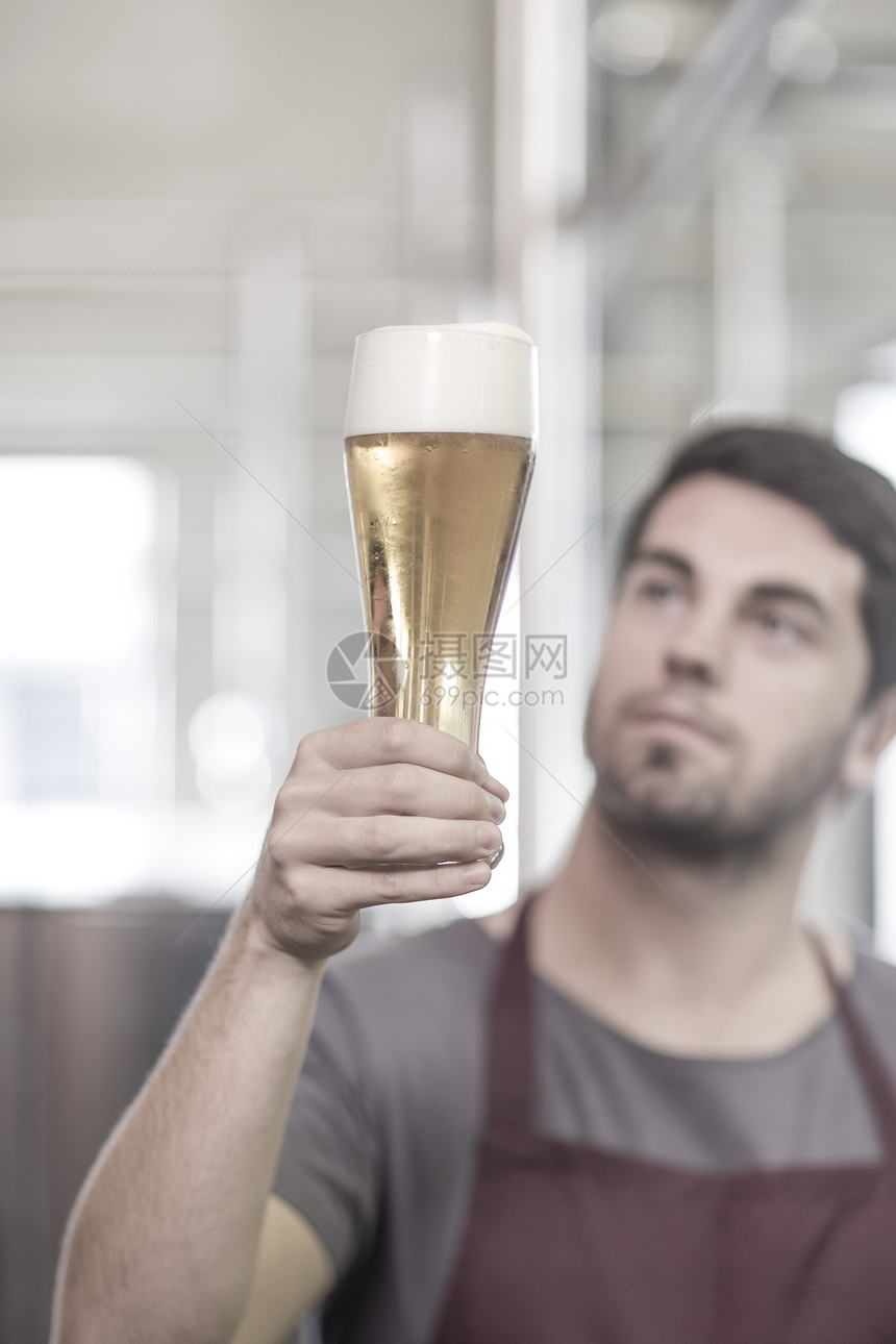 酿酒厂的青年男性手举啤酒杯图片