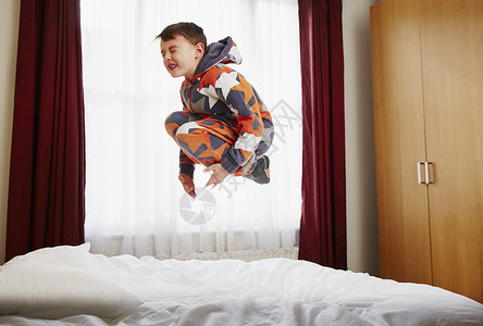 年轻男孩在床上跳跃图片