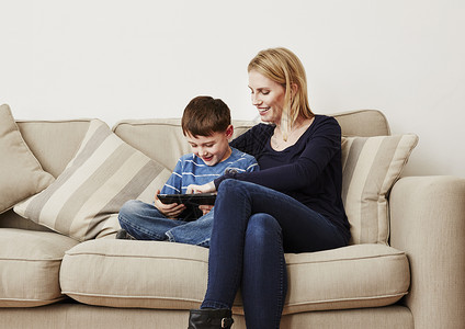 年轻男孩与母亲一起玩平板电脑图片