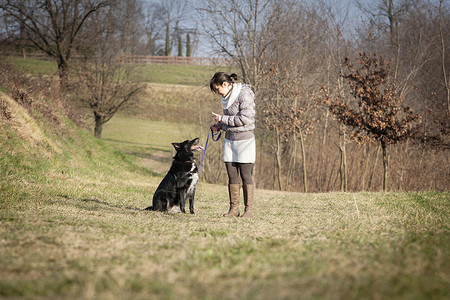 年轻女子和狗狗一起在野外行走图片