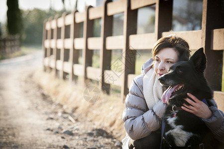 年轻女子和狗狗在乡村车道上的肖像高清图片