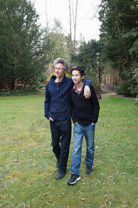 成年男子和十几岁的儿子在花园中行走图片