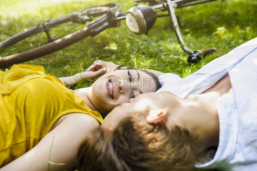 躺在草地上手牵手的年轻夫妇图片