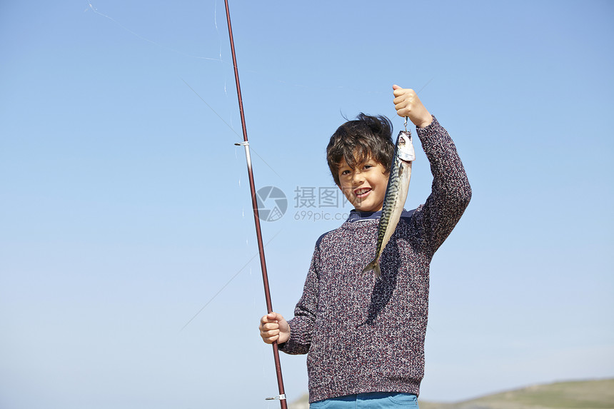 男孩拿着钓鱼杆和鱼图片