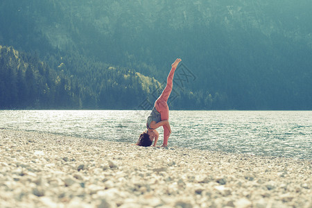 湖边坐瑜伽的年轻女性图片