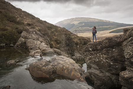 妇女站在苏格兰赫布里底斯凯岛仙子游泳池岩石上图片