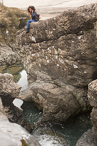 坐在苏格兰赫布里底斯凯岛仙子游泳池岩石上的女人图片