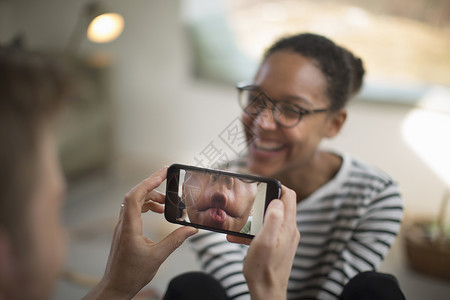 用手机拍照的开心女性图片