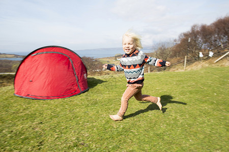 男孩带着帐篷在草地上奔跑图片