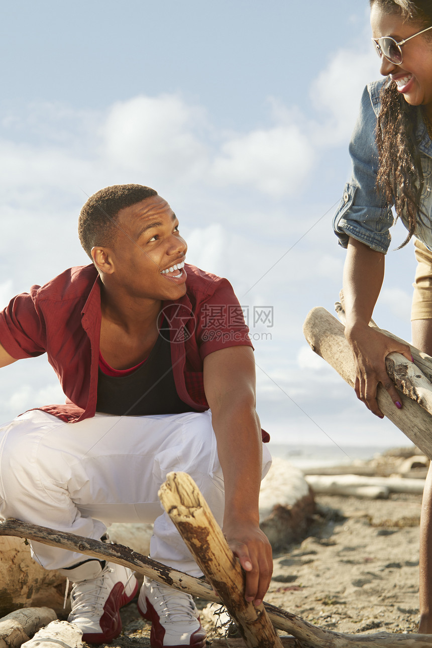 年轻夫妇在海滩上一起收集漂浮木图片