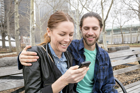 公园长椅上看手机的夫妇图片