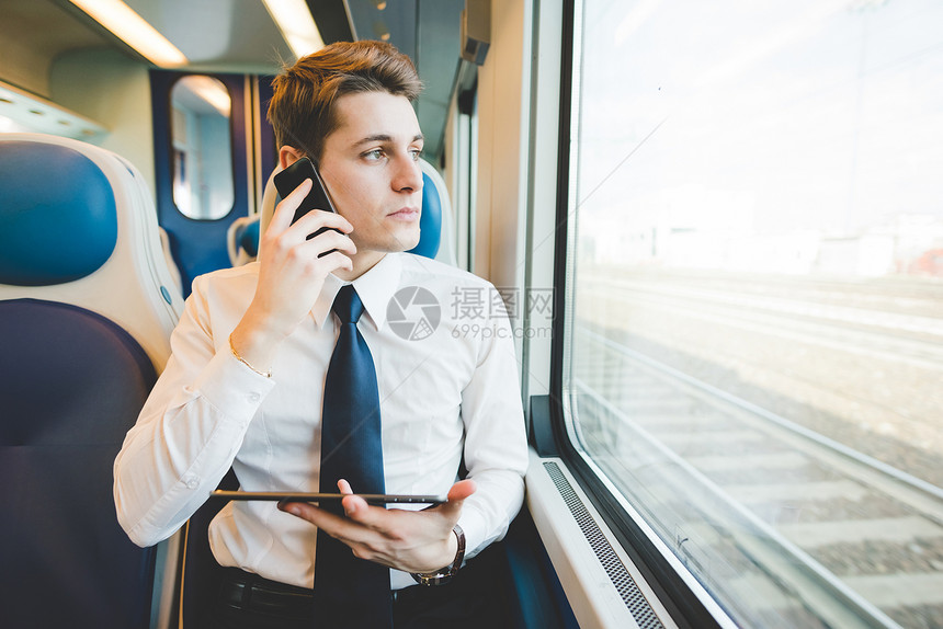 在火车上使用数字平板电脑对青年商人图片