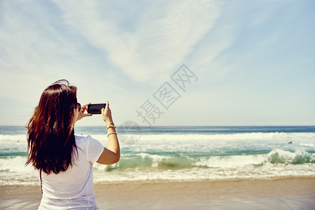 在海滩上拍摄照片的女人图片