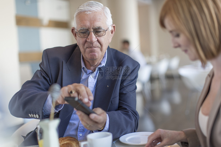高级商人用餐时使用手机图片