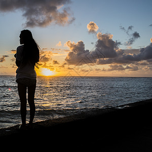 在海边看日出的年轻女子剪影高清图片