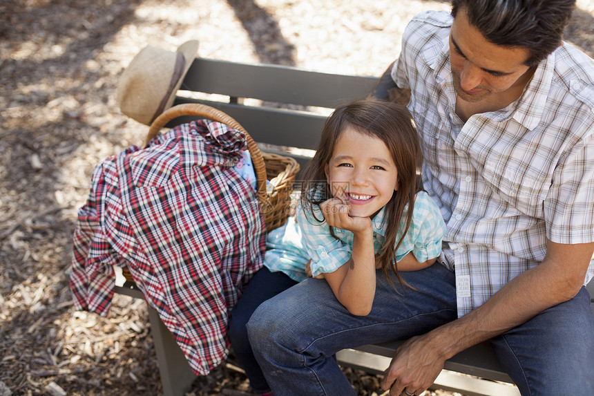 花园中与父亲一起坐在长椅上的女孩肖像图片