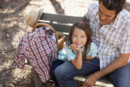 花园中与父亲一起坐在长椅上的女孩肖像图片