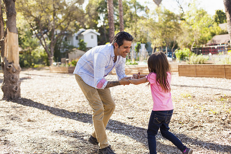 真人女孩女孩和父亲在社区花园玩背景