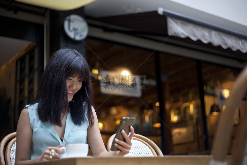 年轻女子坐在咖啡馆外面使用手机图片