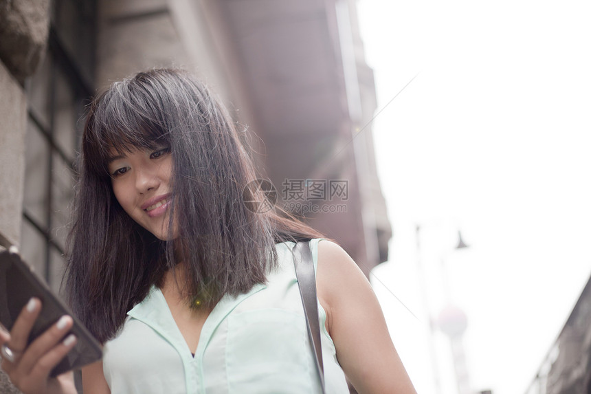 上海市户外使用智能手机的青年女商人图片