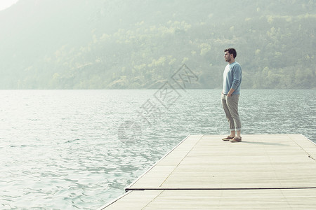 湖边码头上欣赏风景的男子背景图片