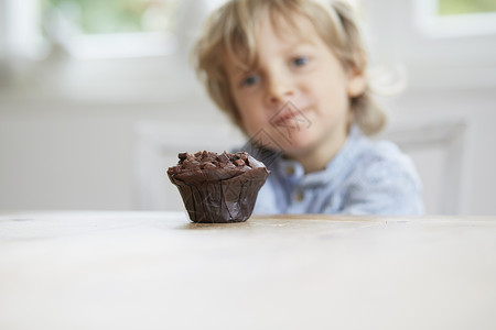 小男孩盯着巧克力松饼看图片