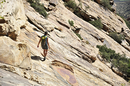 年轻女攀岩者在岩面陡峭的山上行走图片