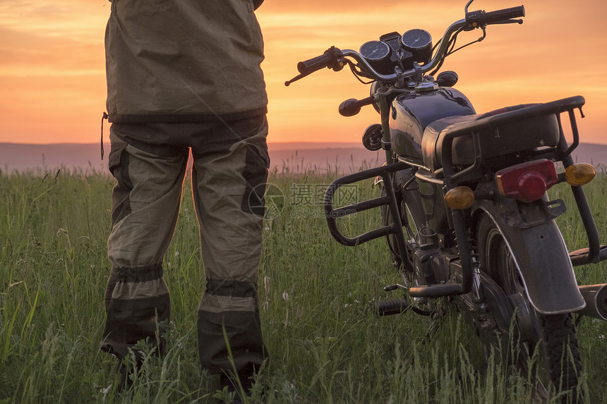 中等成年男子站在田野摩托车旁边日落后视低段图片