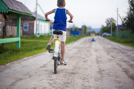 小男孩骑着自行车沿泥土路后视图片