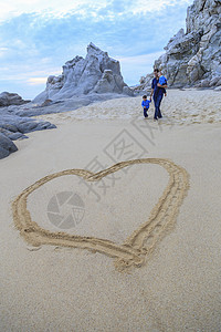 父亲和儿子在沙滩上行走心身在前方图片