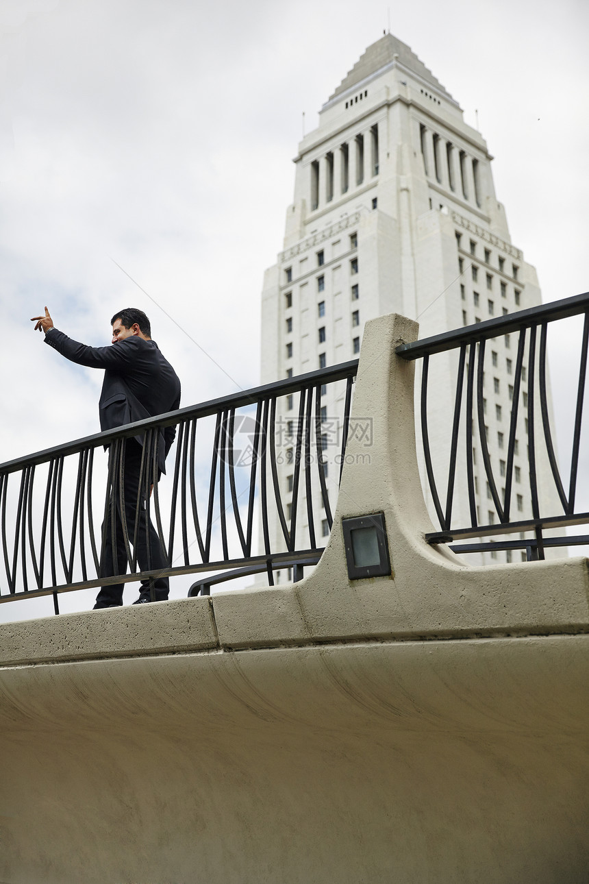美国加利福尼亚州洛杉矶市政厅商人站在人行道上的侧视图手举图片