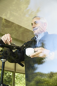 家里的老人喝咖啡透过窗户用望远镜图片