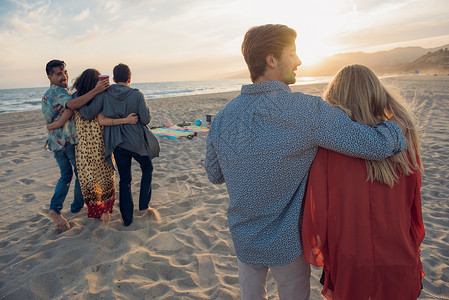 一群朋友站在沙滩上拥抱后视图片