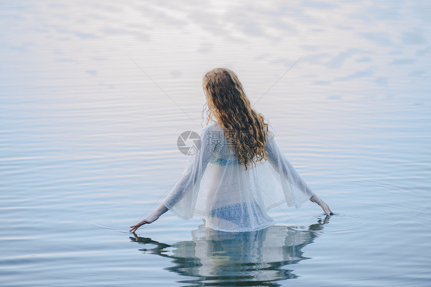年轻女后视镜站在湖面以她的手指撕裂表面图片