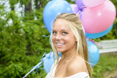 漂亮的年轻女人肖像长金发拿着一堆气球背景图片