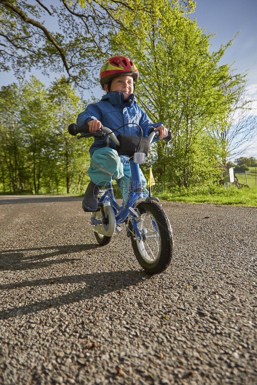 在农村公路上戴着红色头盔骑自行车的男孩图片