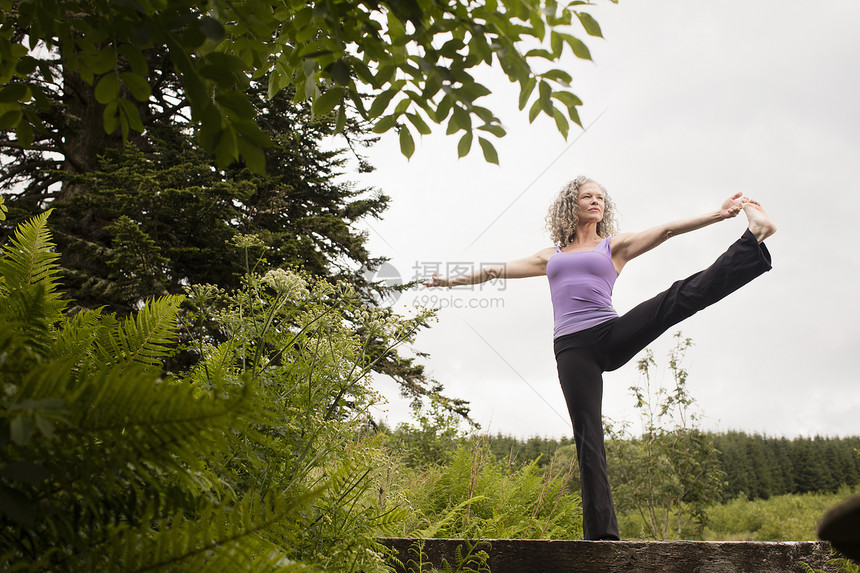 在生态小屋的徒步桥上做瑜伽姿势的成熟女性图片