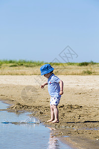 沙滩上的小男孩把沙丢入海中图片