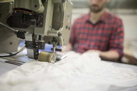 在旧纺织厂缝纫机上编织蕾丝的年轻男性年轻人高清图片素材