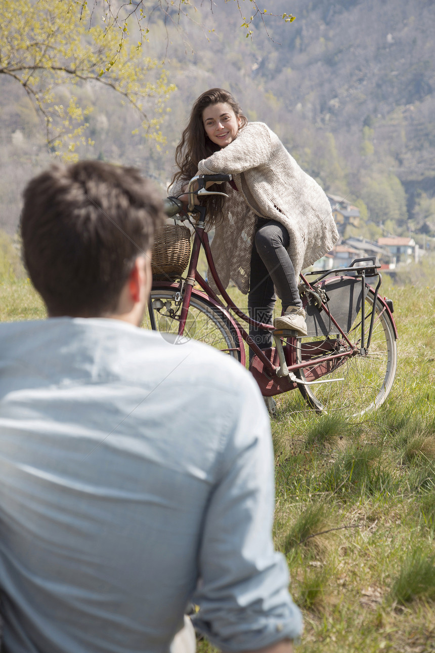 在自行车上与中成年男子聊天的轻妇女肩上图片